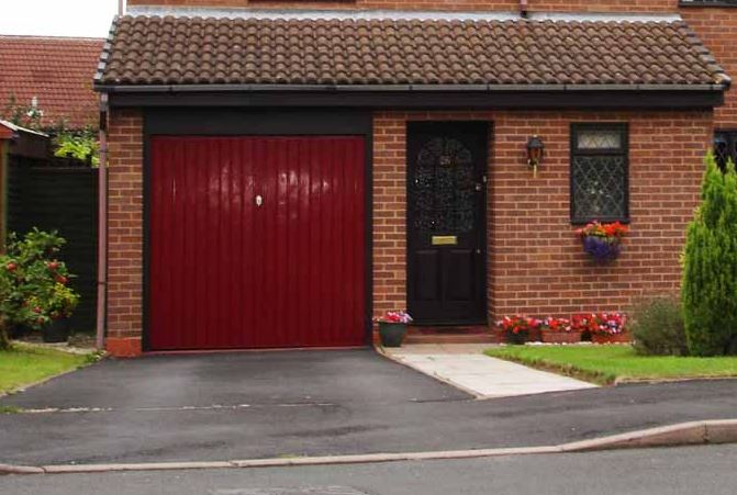 Dropped kerb and smooth tarmac drive into a garage by Drop Kerbs UK